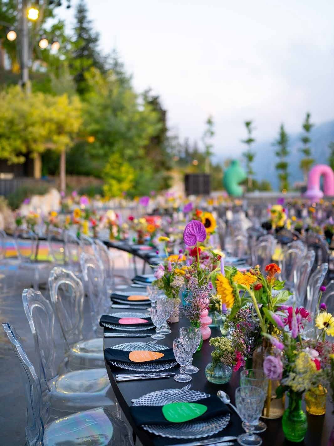 The full length of the reception table styled with mixed color glassware