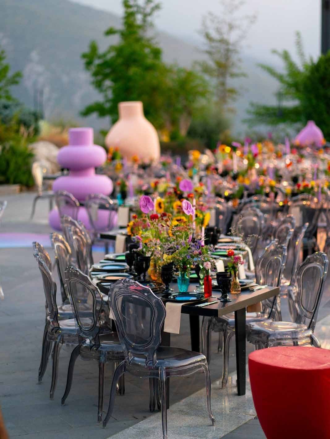 Long reception table styled with colorful glassware, sunflowers and wildflowers